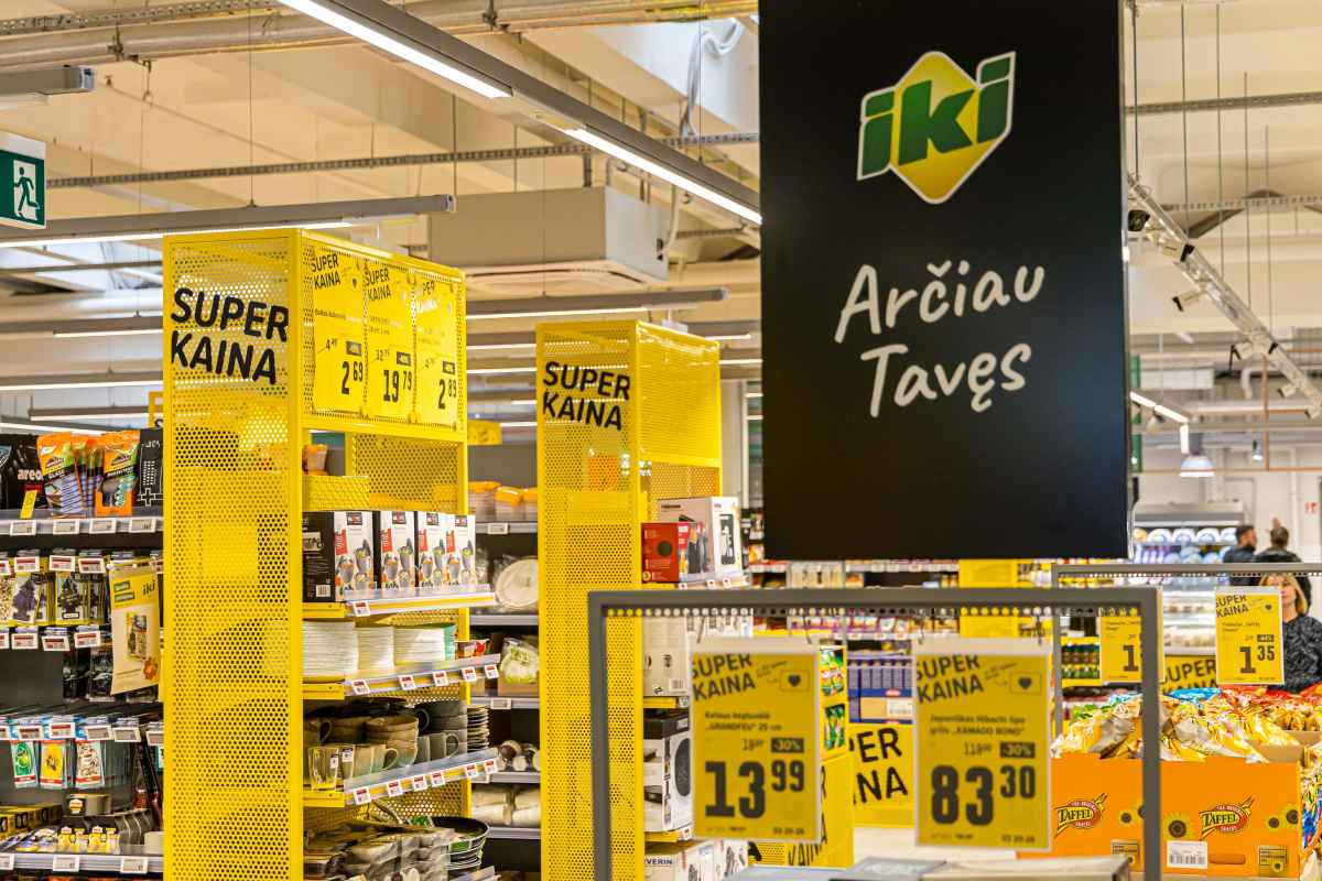 Parduotuvės viduje matomos lentynos su prekėmis ir geltonos etikečių ženklai su užrašu super kaina.